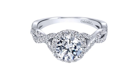 A white gold Gabriel & Co. engagement ring with a round cut center stone, diamond halo, and intertwining shanks