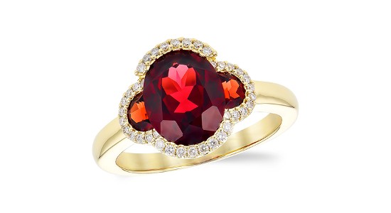 A gold ring featuring a large ruby center stone and two smaller accent rubies on either side as well as round cut diamonds
