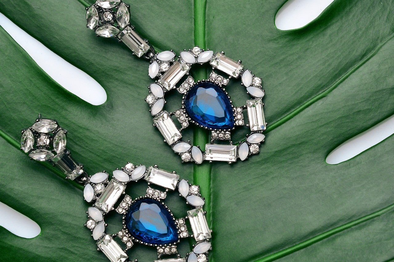 Sapphire and diamond drop earrings on a palm frond
