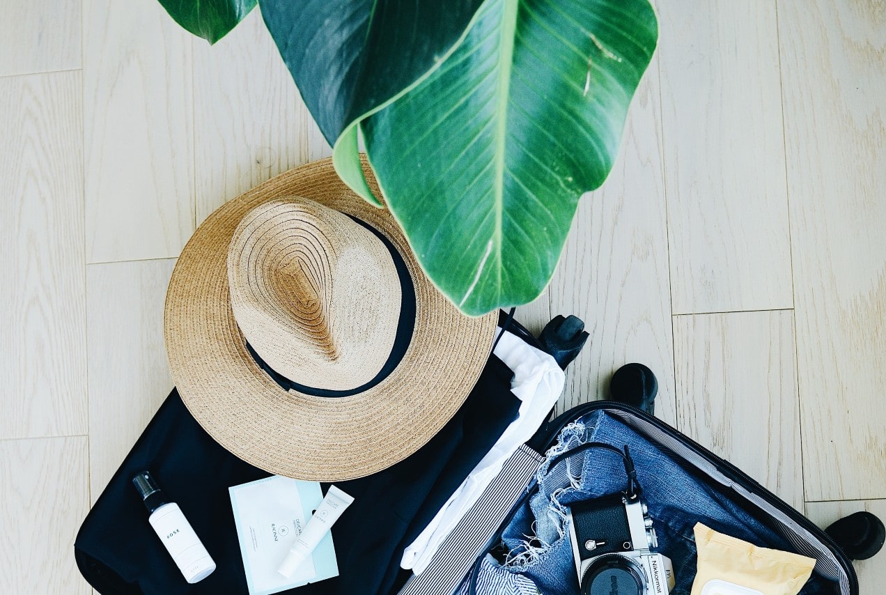 An assemblage of summer travel wear in a suitcase
