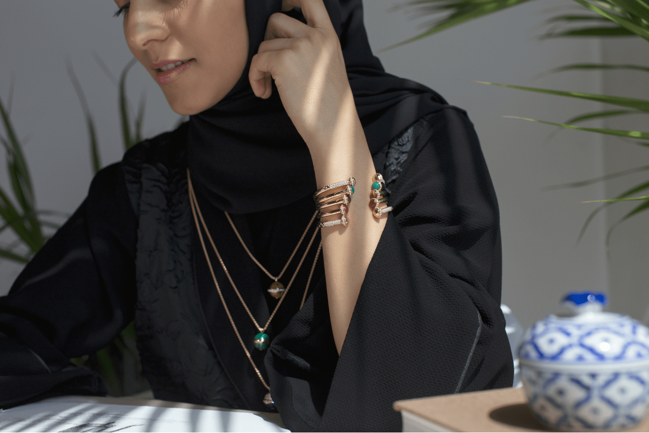 A fashionable lady in hijab wears a plethora of gold bracelets and necklaces