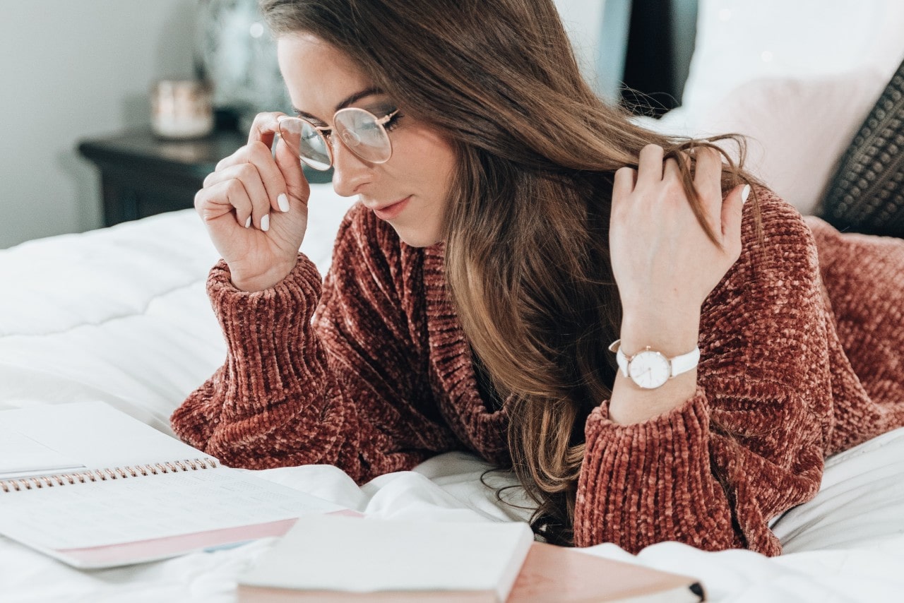 A woman looking at her planner with books next to her while wearing a Citizen watch