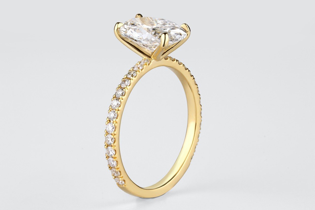 a yellow gold engagement ring with side stones and an oval cut center stone