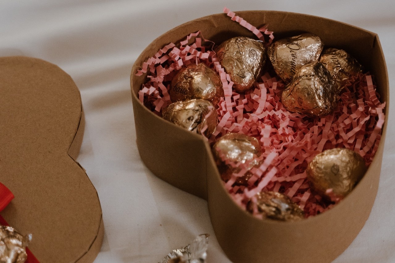 A heart-shaped box contains tissue paper and chocolates.