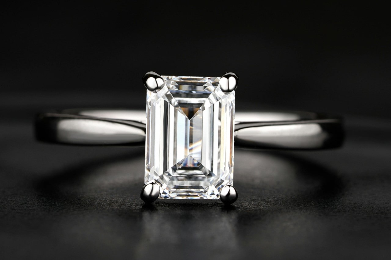 A close-up of a simple yet mesmerizing solitaire engagement ring with an emerald cut center stone.