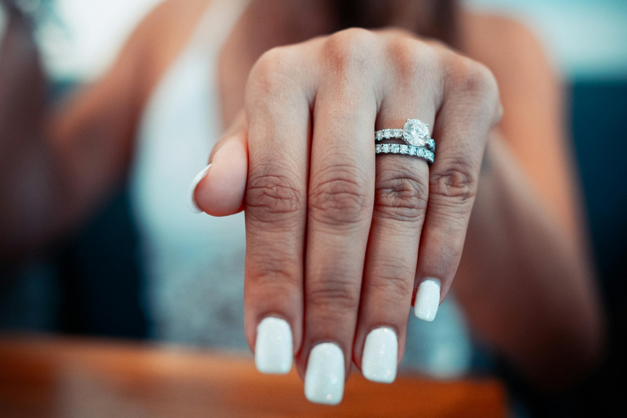 a woman’s extended hand adorned with a matching engagement ring and wedding band