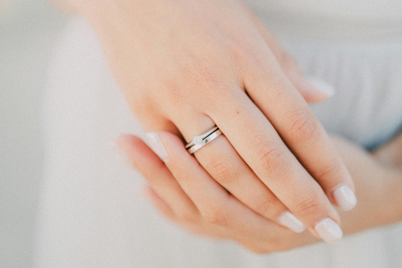 a bride’s hands adorned with a matching silver engagement ring and wedding band