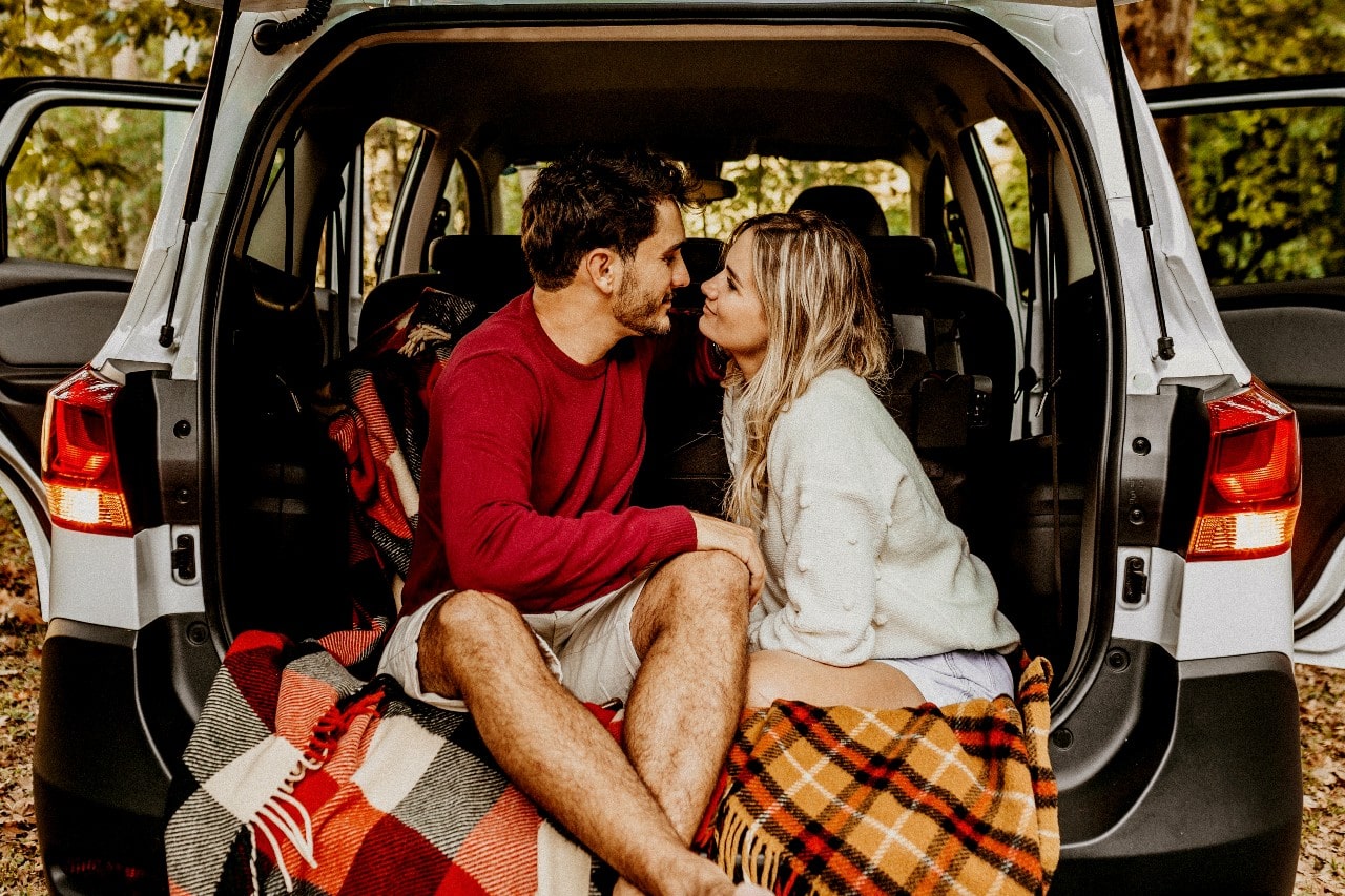 A happy couple looking upon each other lovingly in the back of their SUV.