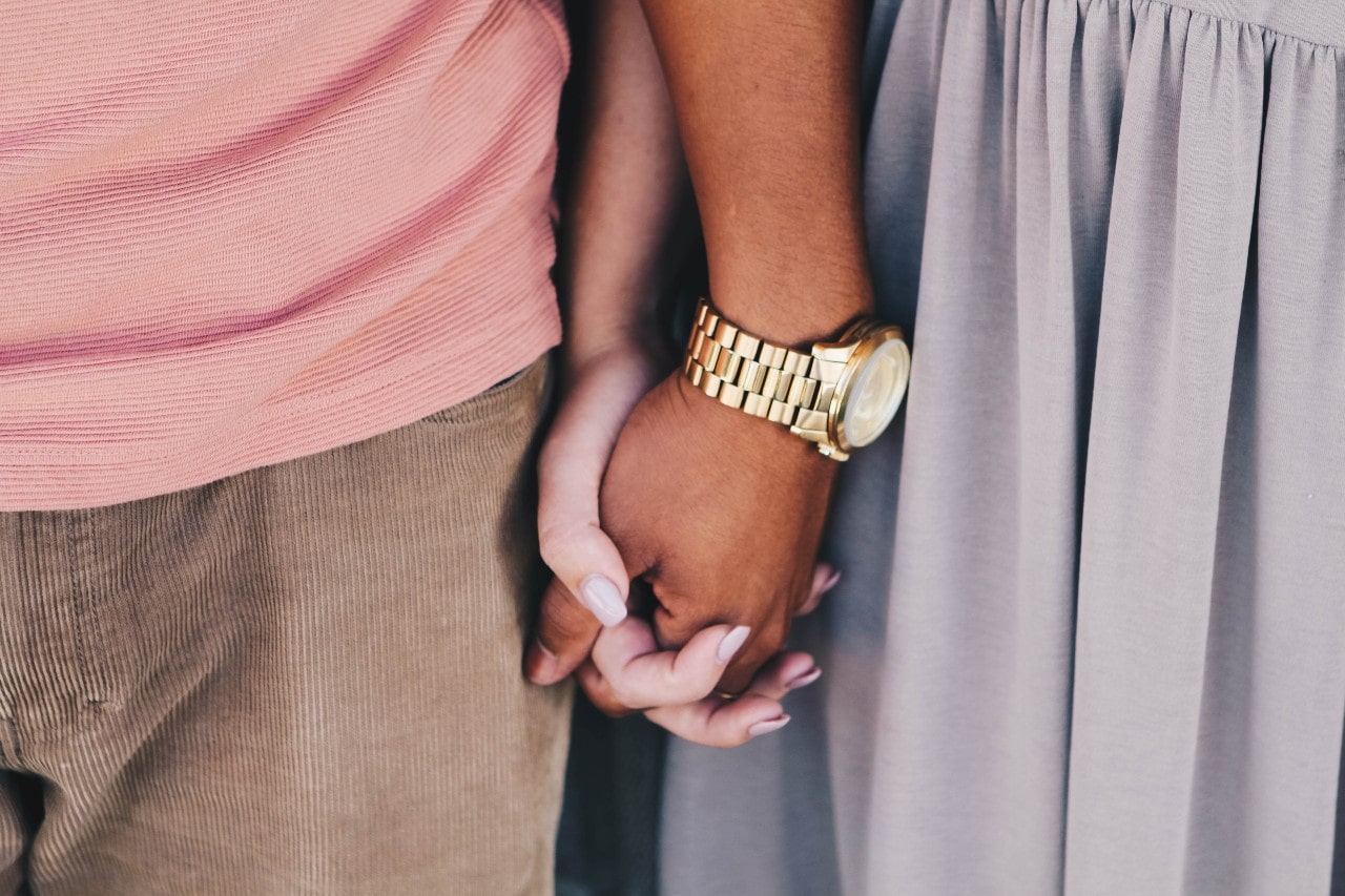 a man and woman holding hands, the man wearing a gold watch