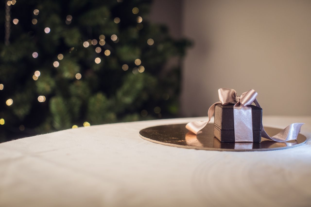 a ring box with a box sitting on a table next to a christmas tree