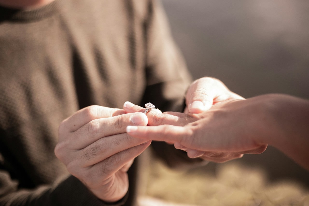 a man sliding an engagement ring on a woman’s finger