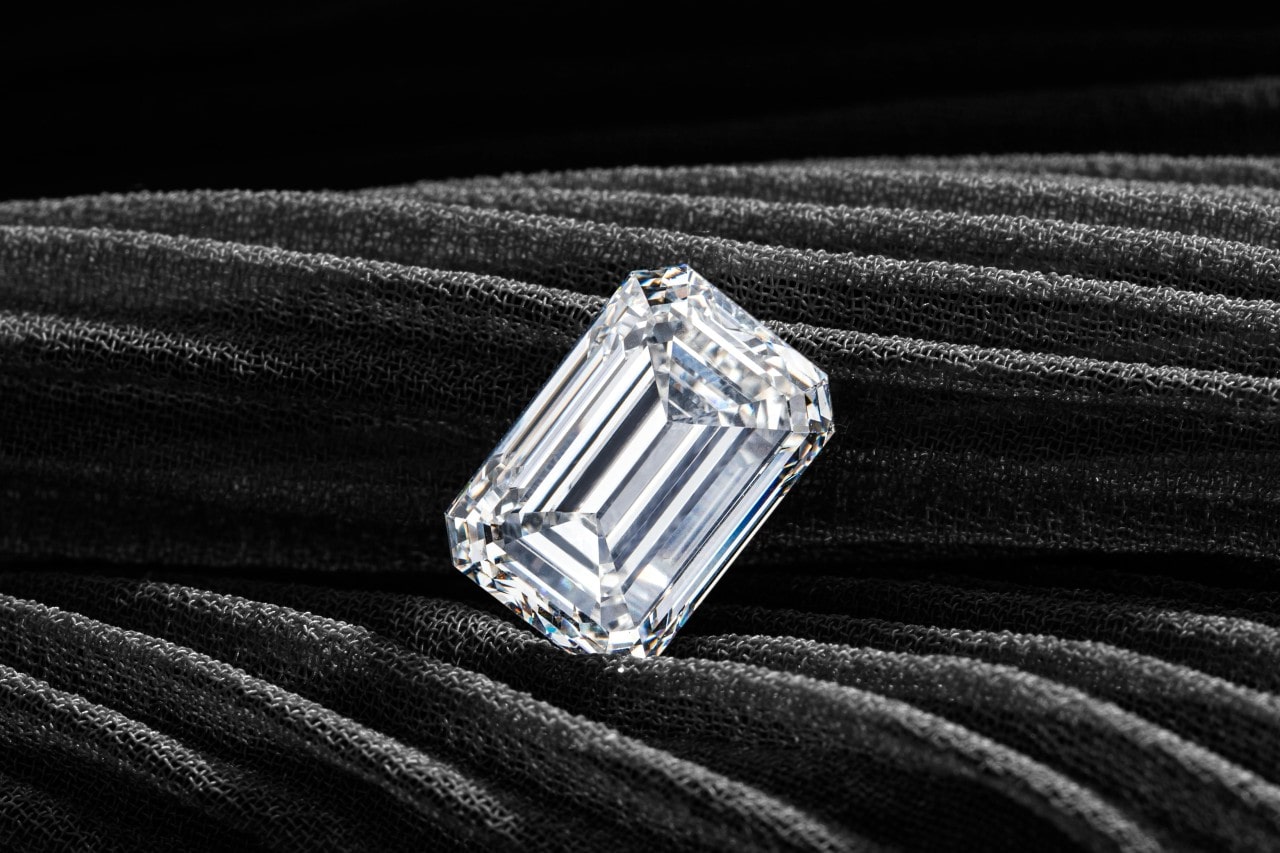 an emerald cut diamond close up against a piece of gray fabric