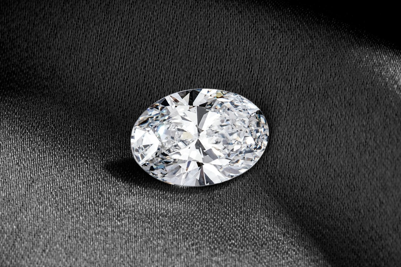 an oval cut diamond against a piece of gray fabric