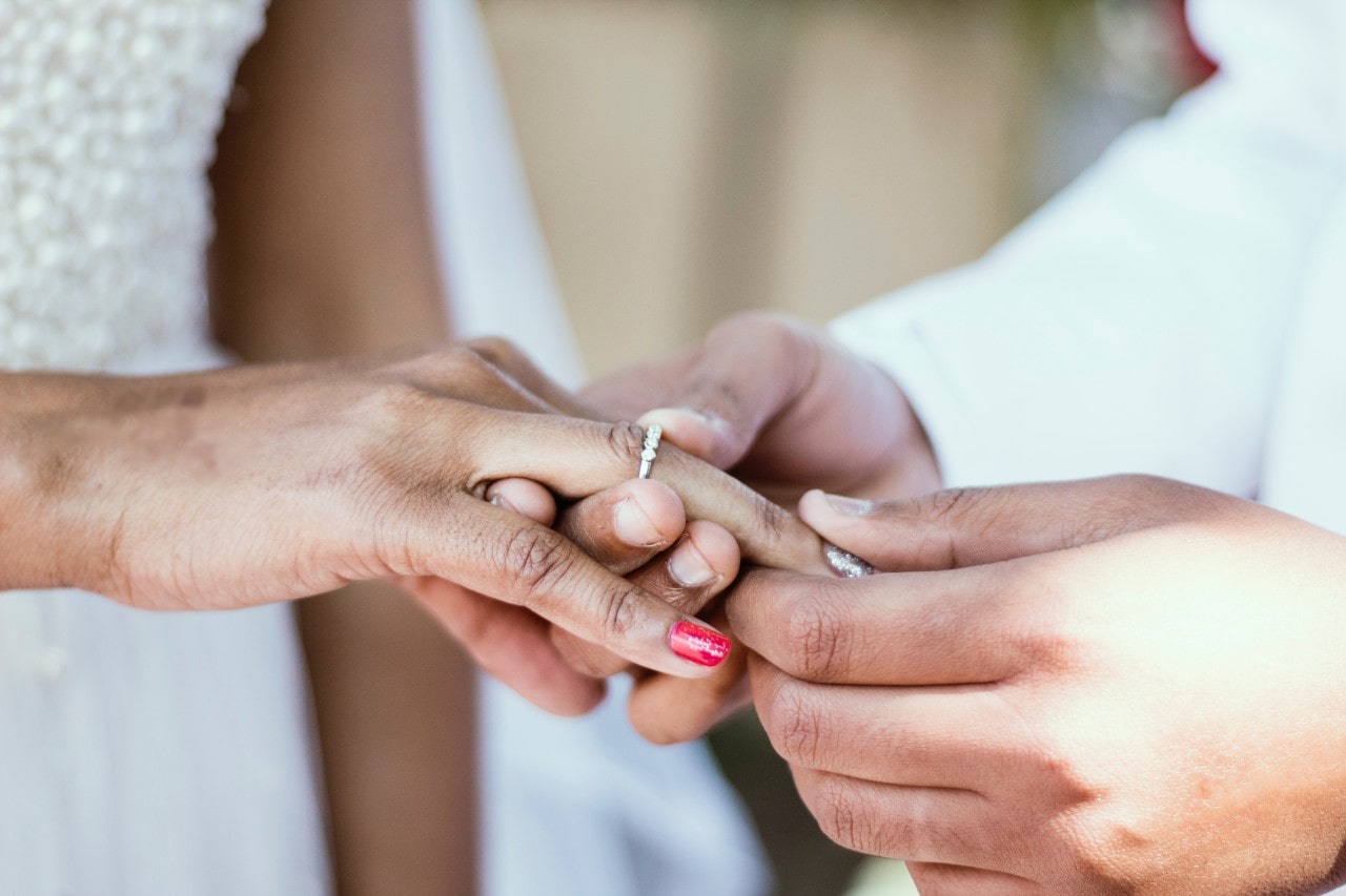 A groom slips a diamond wedding band on his bride’s finger during the ceremony.