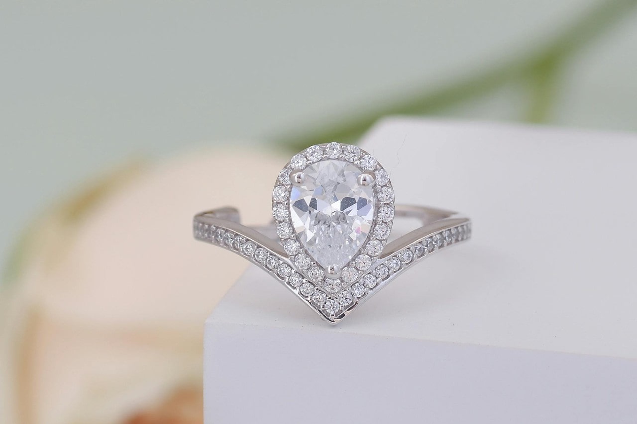 a pear shape engagement ring with a halo and side stones