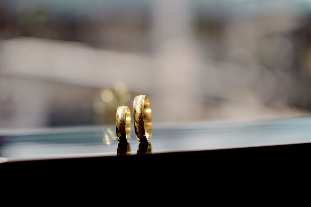 A pair of matching gold wedding bands sit in a window sill.