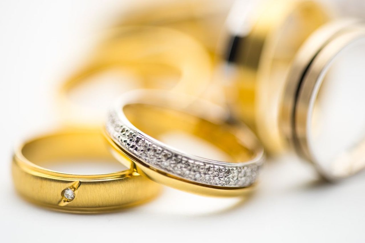 A variety of gold wedding bands sit on a white surface.