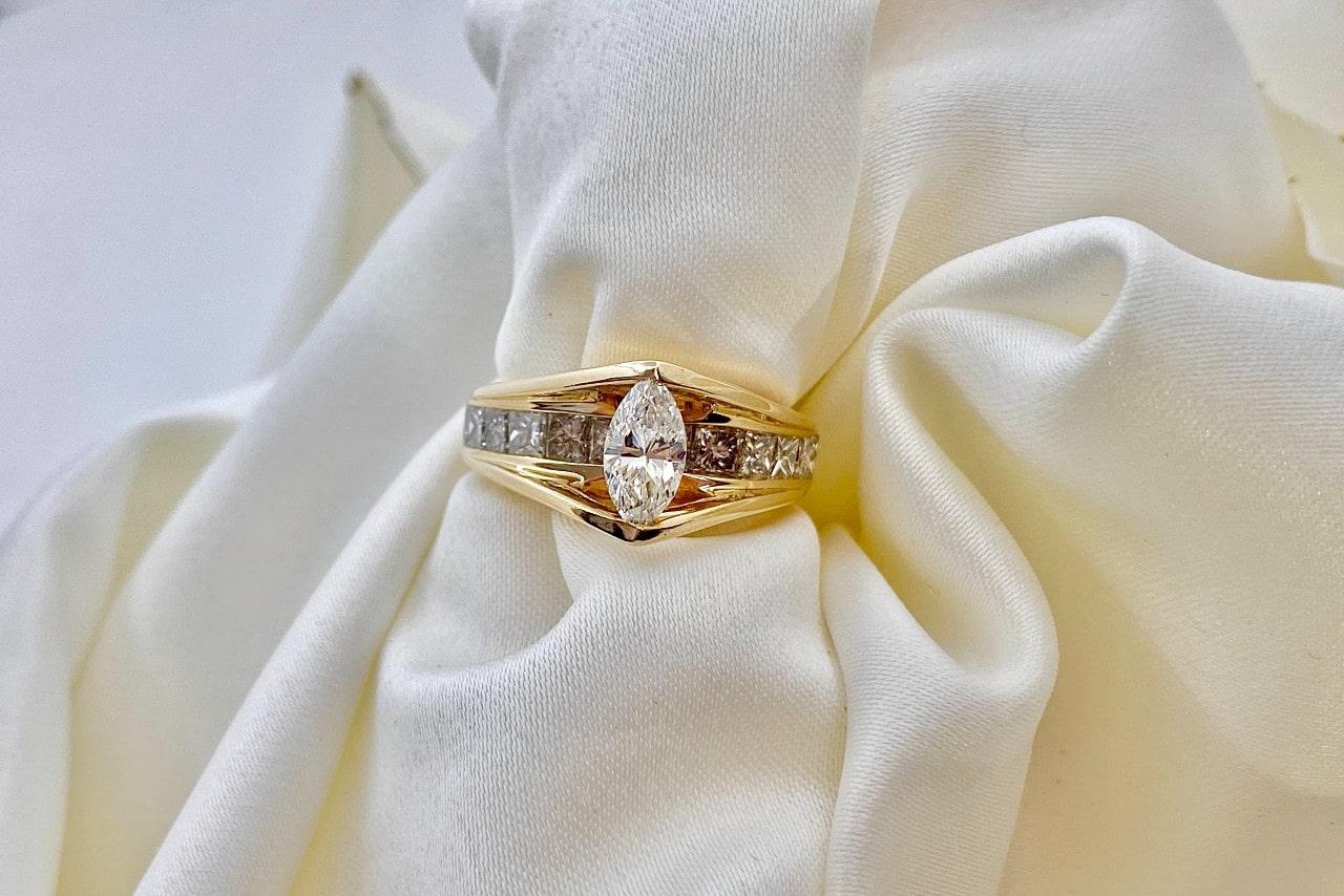 a unique yellow gold engagement ring with a marquise cut center stone and princess side stones